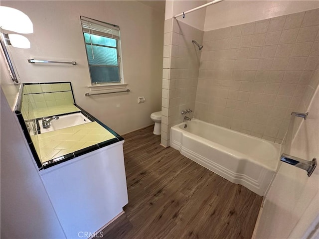 full bathroom with vanity, tiled shower / bath combo, wood-type flooring, and toilet