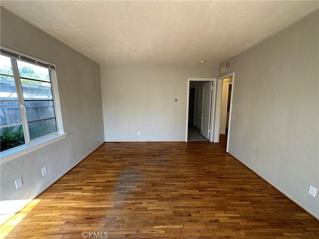 unfurnished room featuring hardwood / wood-style flooring and a textured ceiling