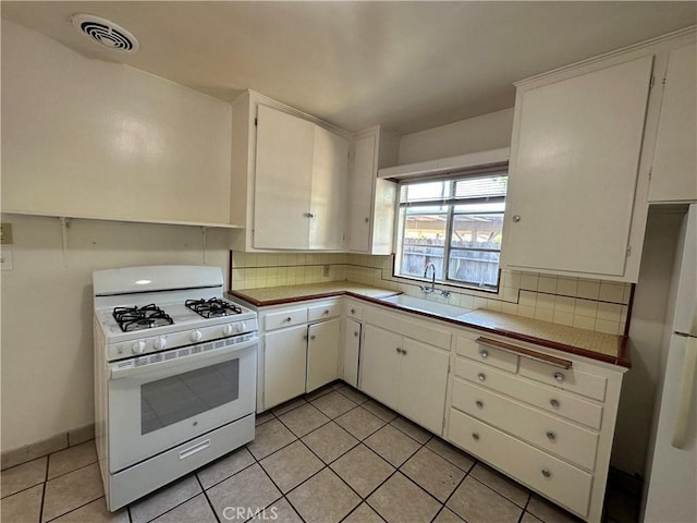 kitchen featuring tasteful backsplash, white cabinetry, sink, and white appliances