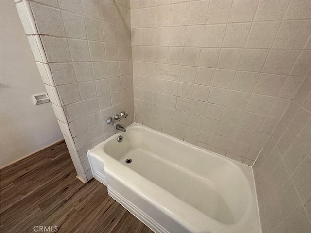 bathroom with hardwood / wood-style flooring and tiled shower / bath combo