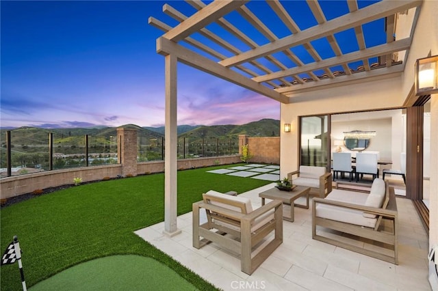 patio terrace at dusk featuring a mountain view, outdoor lounge area, a yard, and a pergola