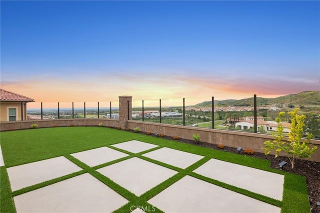 yard at dusk featuring a mountain view and a patio area