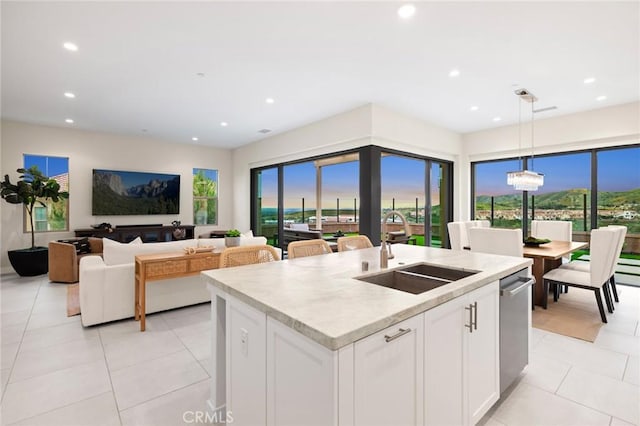 kitchen with sink, white cabinets, hanging light fixtures, a kitchen island with sink, and a healthy amount of sunlight