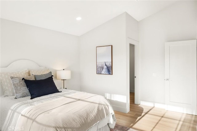 bedroom featuring lofted ceiling, baseboards, and wood finished floors