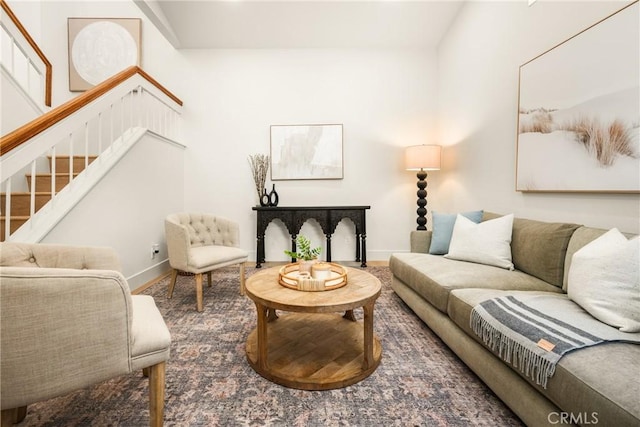 living room featuring baseboards and stairway