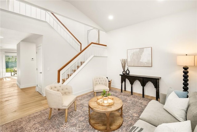 living area with recessed lighting, wood finished floors, high vaulted ceiling, baseboards, and stairs