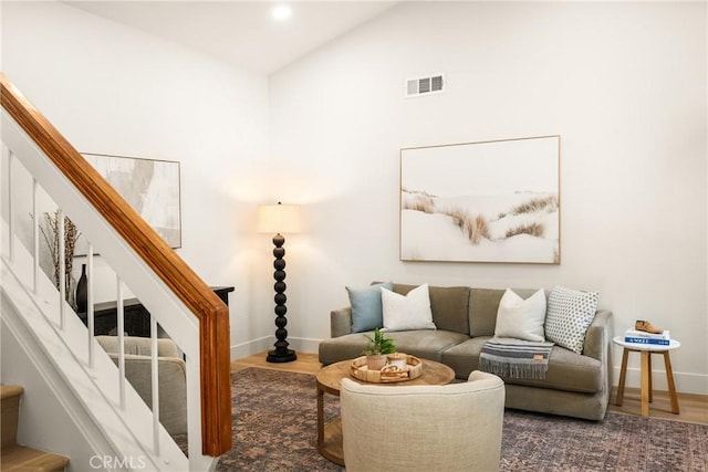 living room featuring baseboards, visible vents, wood finished floors, stairs, and vaulted ceiling