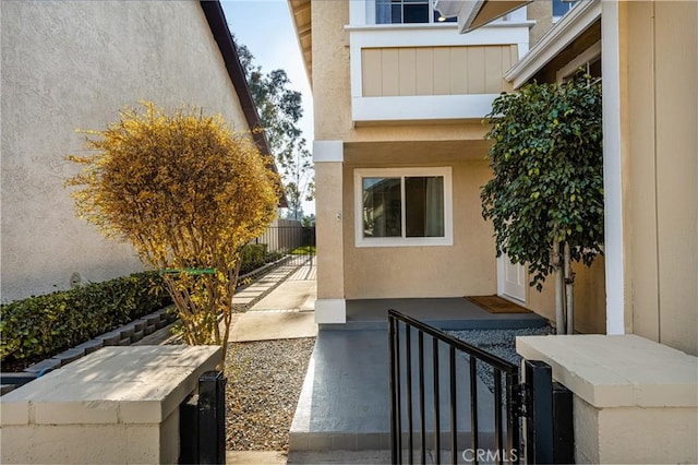 view of exterior entry with fence and stucco siding