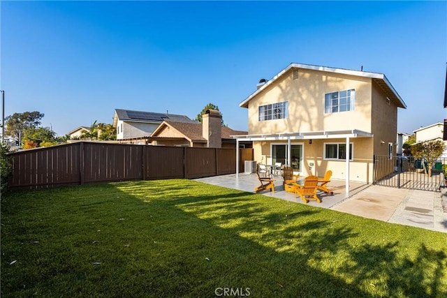 rear view of house with stucco siding, a fenced backyard, a lawn, and a patio