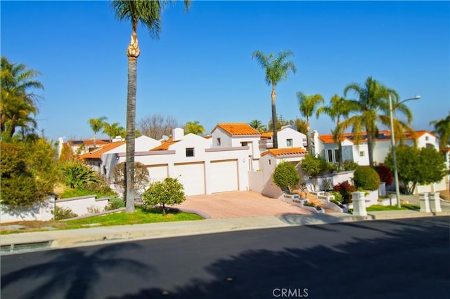 mediterranean / spanish house featuring a residential view, driveway, an attached garage, and stucco siding