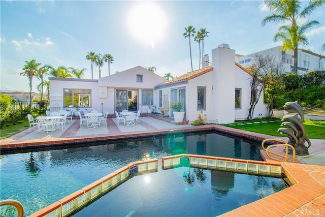 back of house featuring a patio, fence, a pool with connected hot tub, and stucco siding