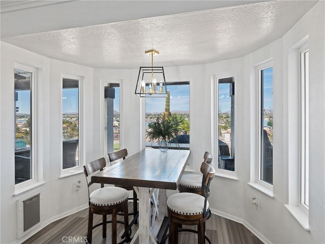 dining room featuring a notable chandelier, a textured ceiling, baseboards, and wood finished floors