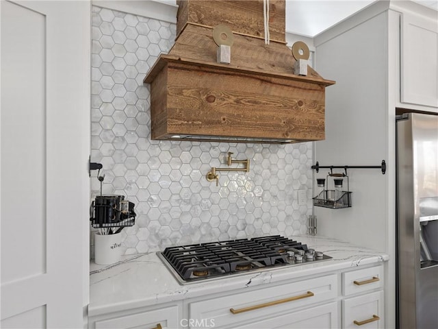 kitchen featuring light stone countertops, tasteful backsplash, appliances with stainless steel finishes, and white cabinets