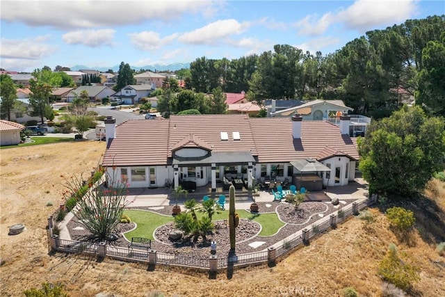 back of property with a tile roof, a residential view, fence, and a patio