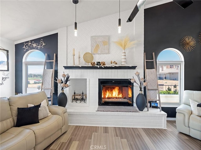 living room with plenty of natural light, a brick fireplace, and wood finished floors