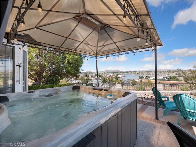 view of patio with a water view, a hot tub, and a gazebo