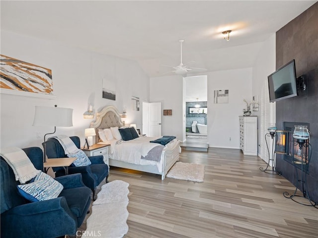 bedroom featuring light wood-type flooring, baseboards, vaulted ceiling, and connected bathroom