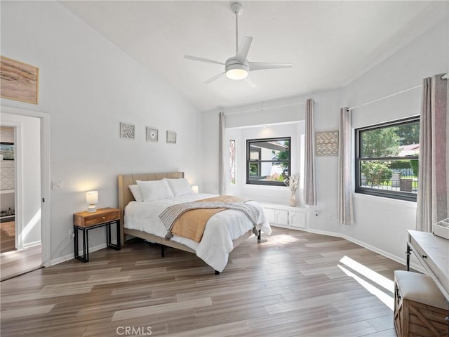 bedroom with a ceiling fan, vaulted ceiling, light wood-style flooring, and baseboards