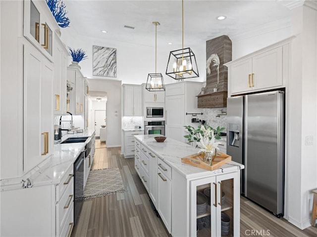 kitchen with pendant lighting, appliances with stainless steel finishes, glass insert cabinets, white cabinets, and a sink