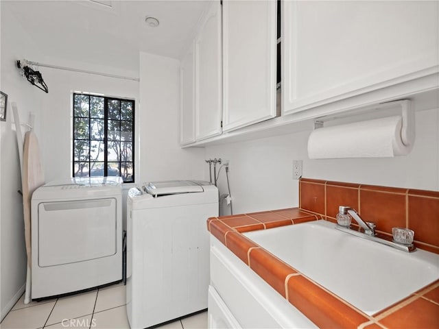 laundry room featuring washing machine and dryer, cabinet space, a sink, and light tile patterned flooring