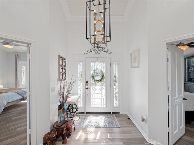 foyer entrance featuring a towering ceiling, baseboards, dark wood-type flooring, and crown molding