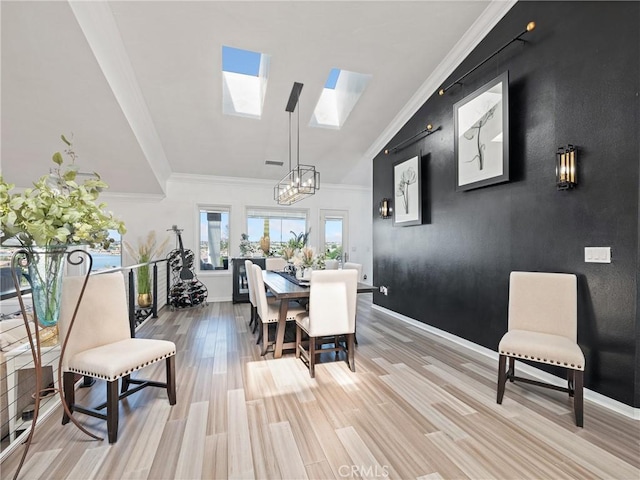 dining space featuring light wood finished floors, baseboards, an accent wall, and a skylight