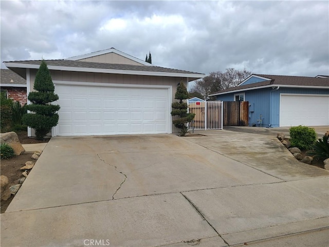 garage with concrete driveway and fence