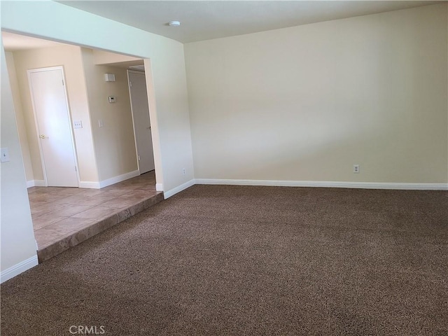 carpeted empty room with baseboards and tile patterned floors