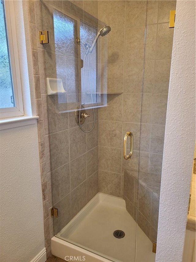 bathroom featuring a textured wall and a shower stall