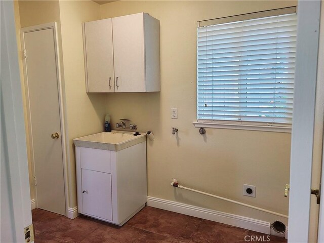 clothes washing area with dark tile patterned flooring, cabinet space, electric dryer hookup, and baseboards