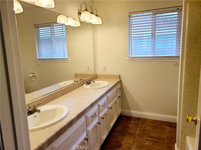 full bath with double vanity, baseboards, a sink, and tile patterned floors