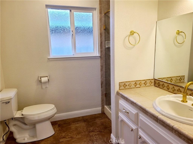 full bathroom with baseboards, toilet, a tile shower, vanity, and backsplash