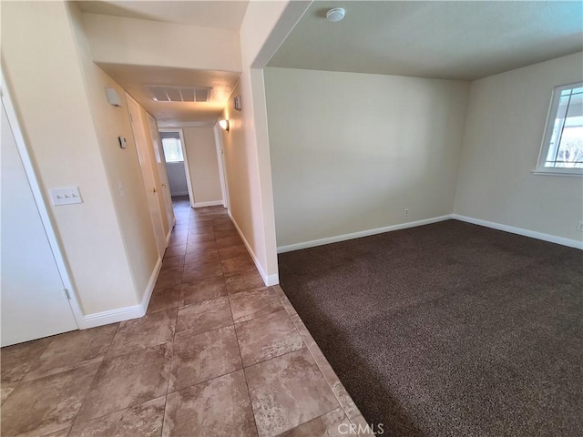 hall featuring baseboards, visible vents, and carpet flooring