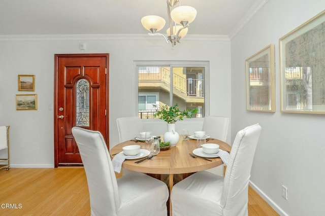 dining space featuring a notable chandelier, ornamental molding, and light wood-type flooring