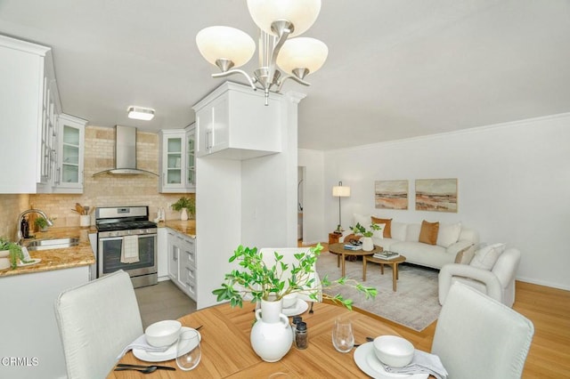 dining area with an inviting chandelier, sink, light hardwood / wood-style flooring, and ornamental molding