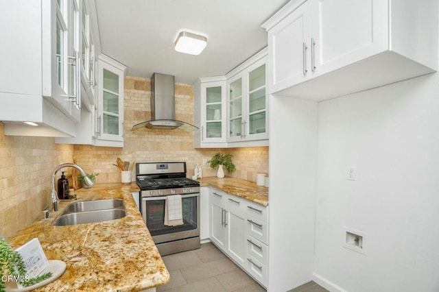 kitchen with sink, white cabinets, backsplash, gas range, and wall chimney range hood