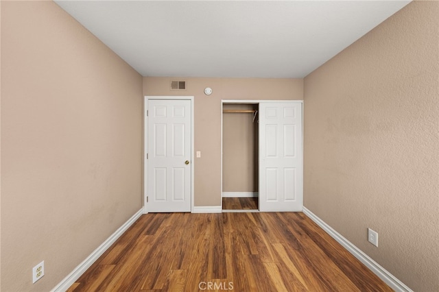 unfurnished bedroom with dark wood-type flooring and a closet