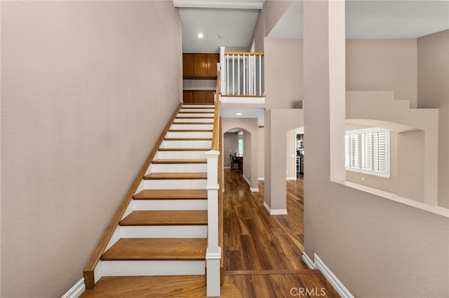 stairway featuring a towering ceiling and hardwood / wood-style floors