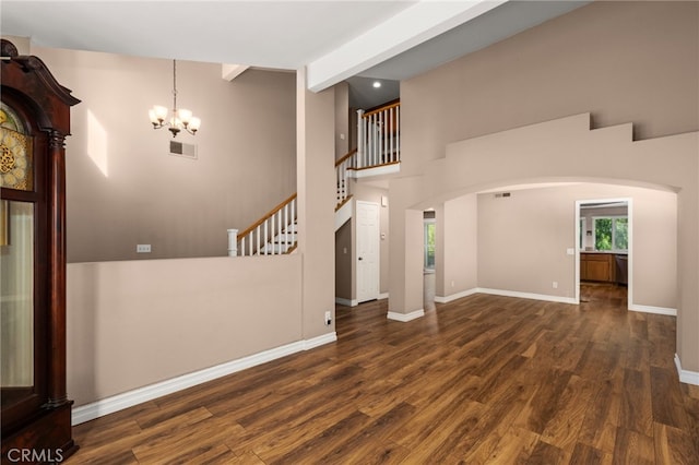 unfurnished living room with a high ceiling, dark hardwood / wood-style flooring, an inviting chandelier, and beam ceiling