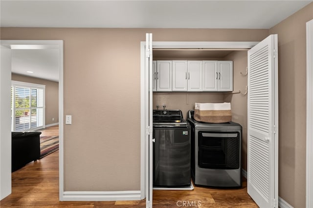 laundry area with cabinets, hardwood / wood-style flooring, and independent washer and dryer