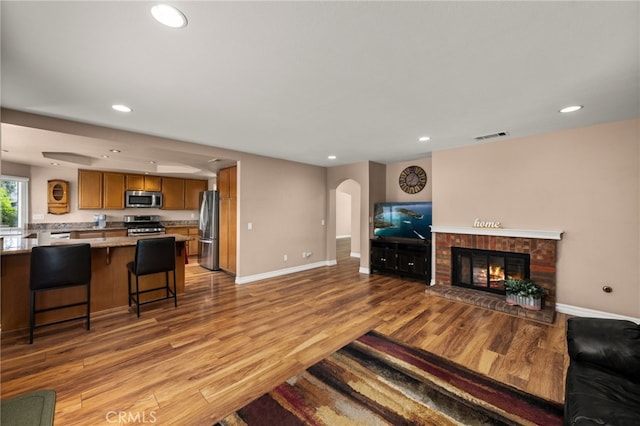 living room with a brick fireplace and light wood-type flooring