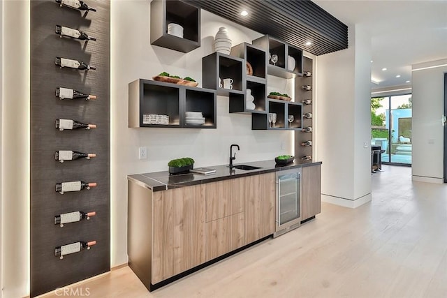 interior space featuring light brown cabinetry, sink, light hardwood / wood-style floors, and beverage cooler