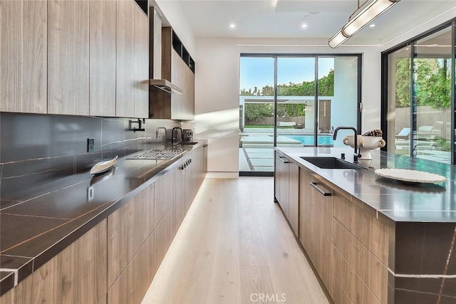 kitchen with black cooktop, sink, decorative backsplash, and light hardwood / wood-style flooring