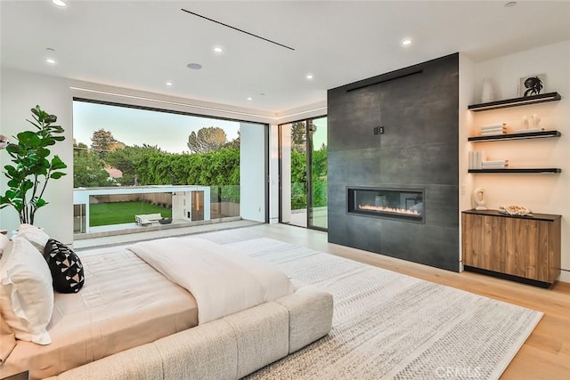 bedroom featuring light hardwood / wood-style flooring, a tile fireplace, and access to outside