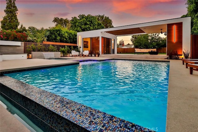 pool at dusk with an outbuilding and a patio