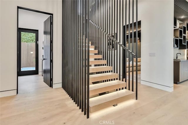 staircase with hardwood / wood-style floors and sink