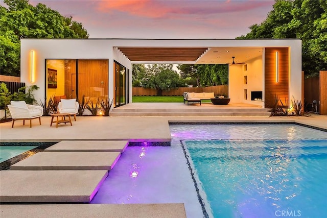 pool at dusk featuring an outbuilding, an outdoor living space, and a patio area