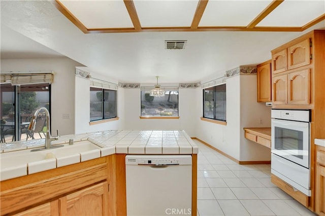 kitchen featuring a warming drawer, tile countertops, visible vents, a sink, and white appliances