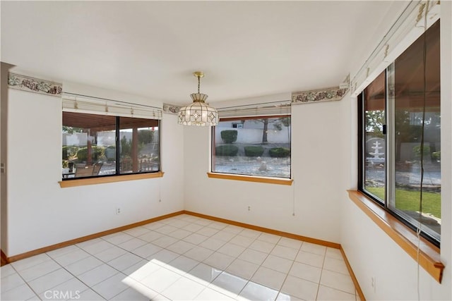 unfurnished room featuring a chandelier, tile patterned floors, and baseboards