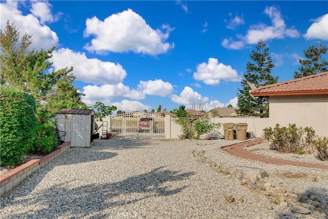 view of yard with a shed, a gate, fence, and an outdoor structure